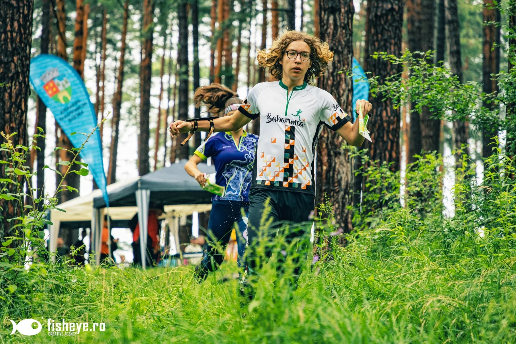 A participant at an orienteering checkpoint in the forest